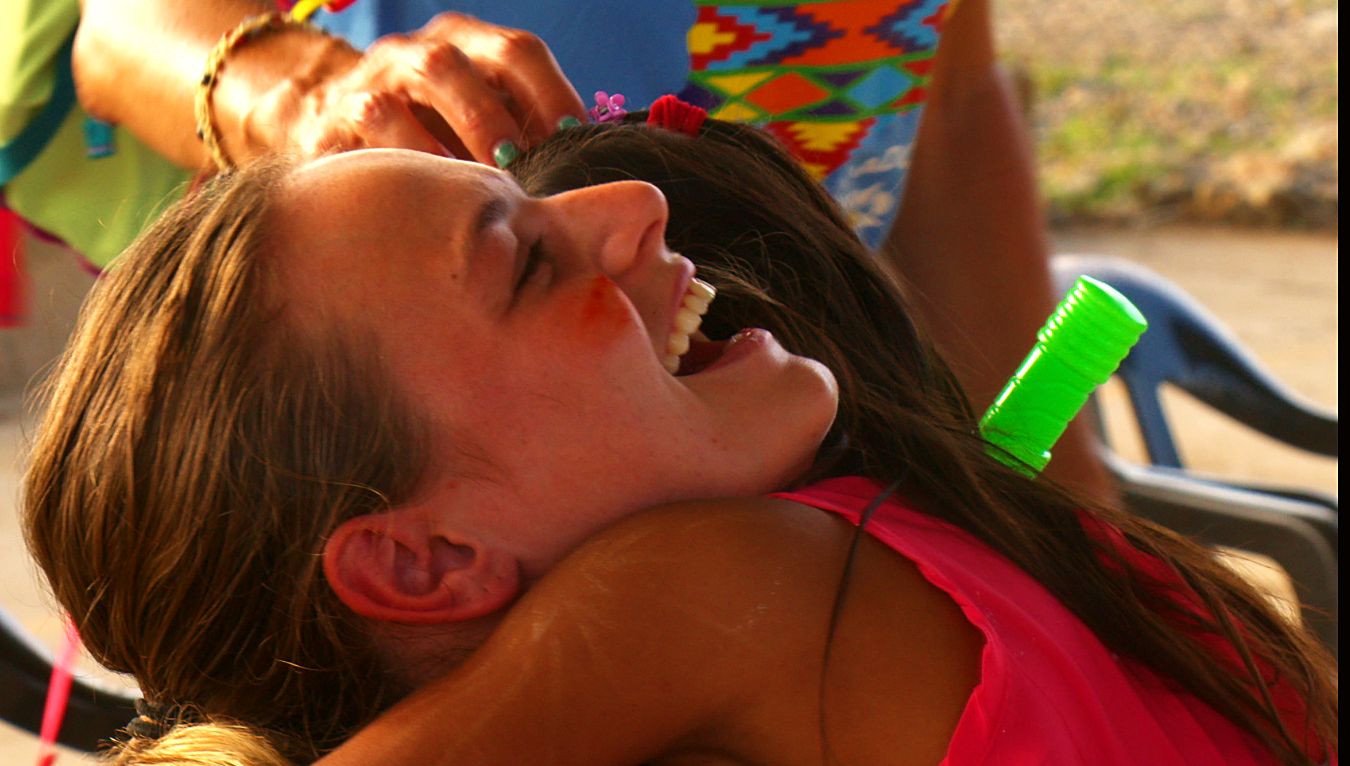 A volunteer laughing as a girl hugs her